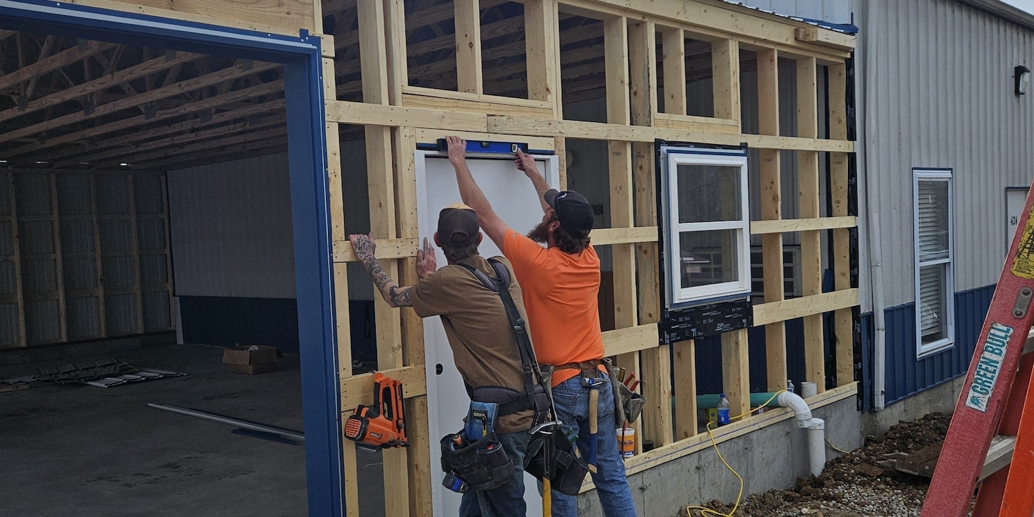 Two employees framing out a door for a commercial project