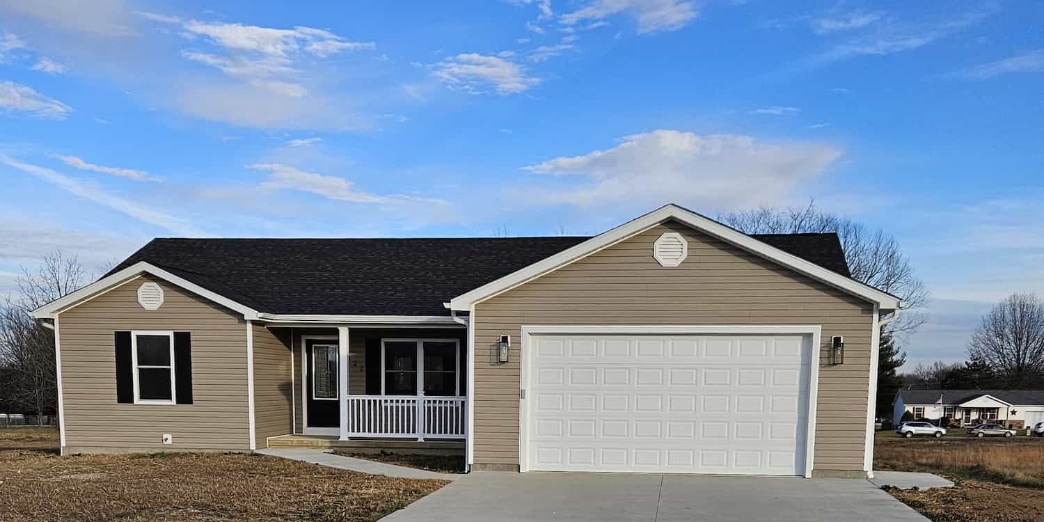 A new residential house with white trim, a white garage door, and tan siding