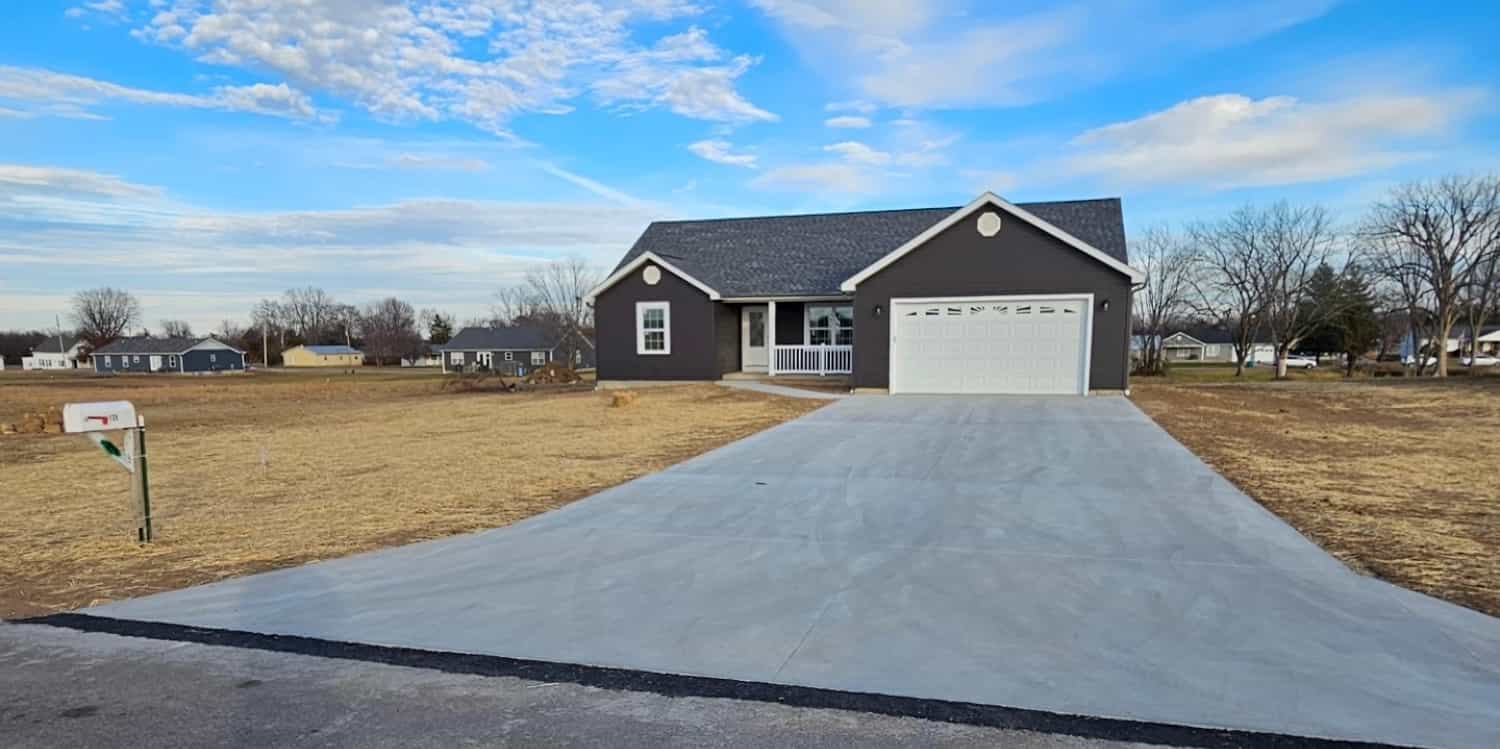 A newly built residential house with dark gray siding, white trim, and a white garage door
