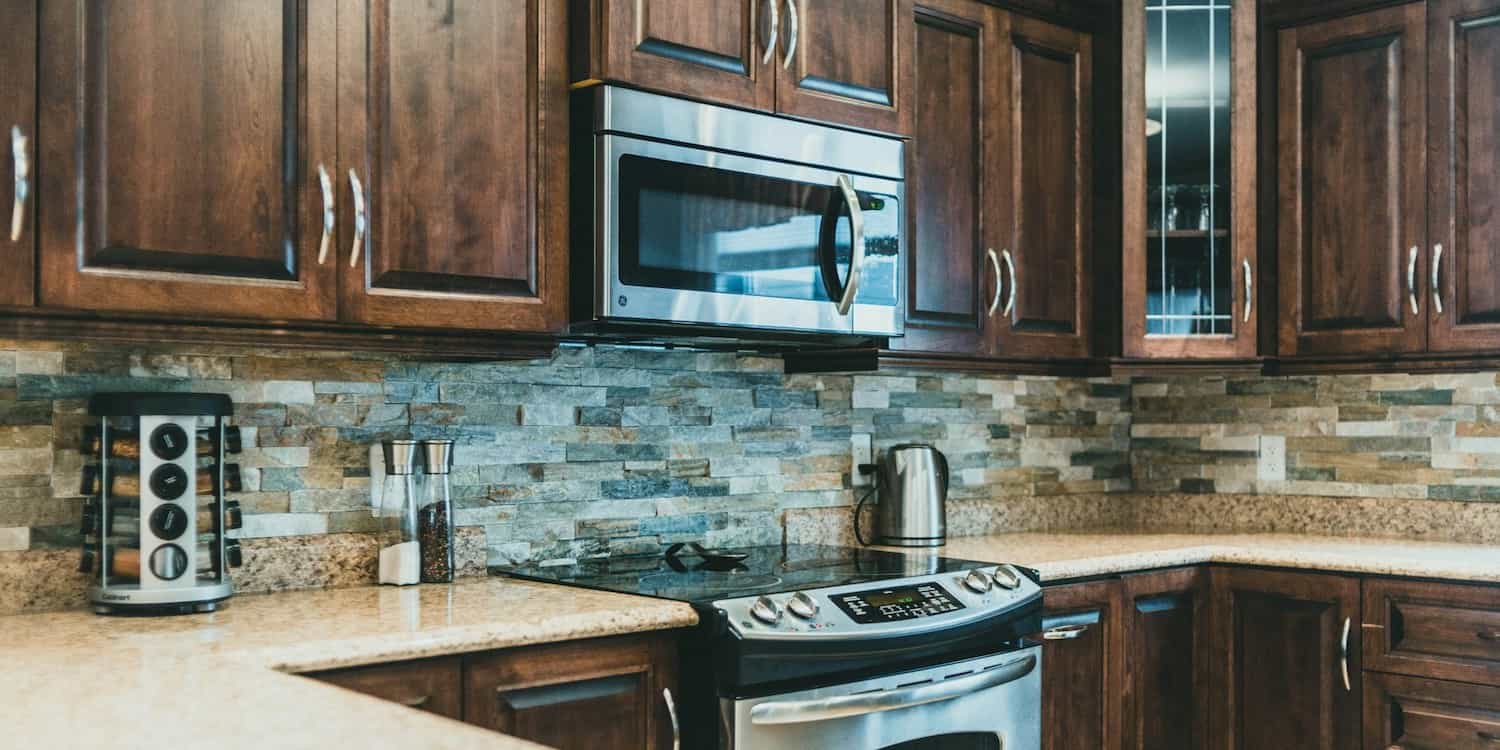 A kitchen showing brown cabinets and a new microwave with a stove